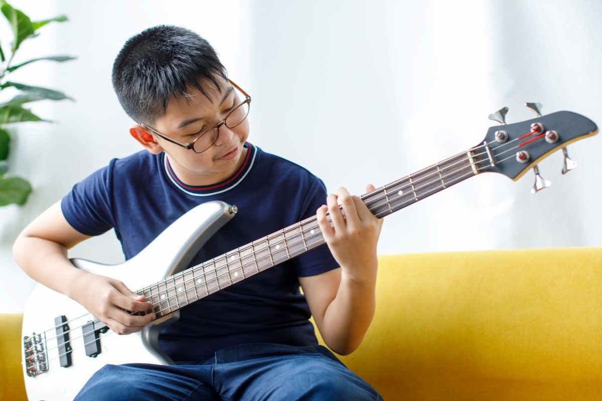 A female child playing Bass Guitar looking at the chords